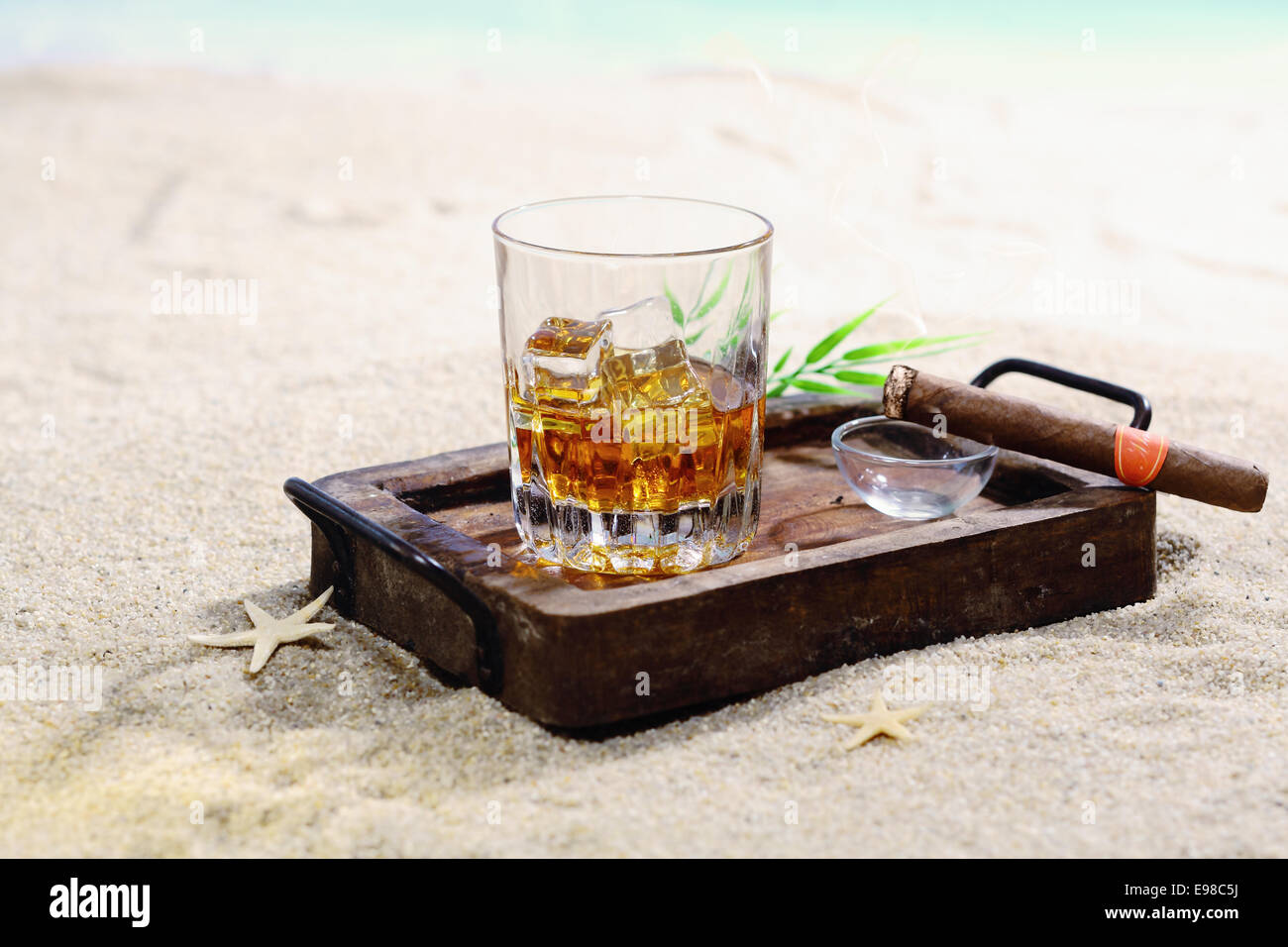 Beautiful image of scotch on the rocks in a classy wooden tray on a sandy beach. Stock Photo