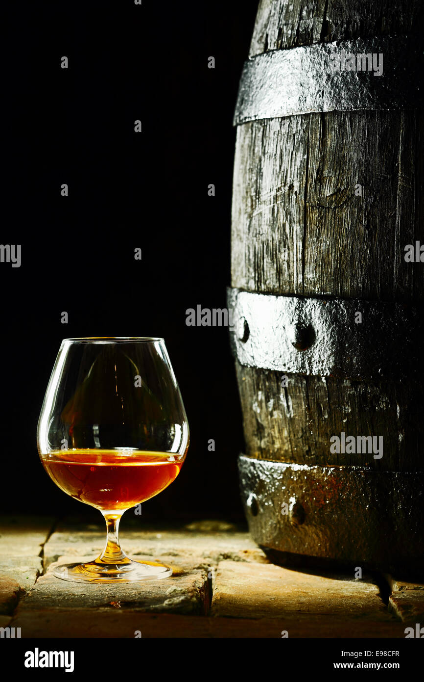 Cognac snifter with glowing golden cognac standing on old flagstones or tiles alongside an old