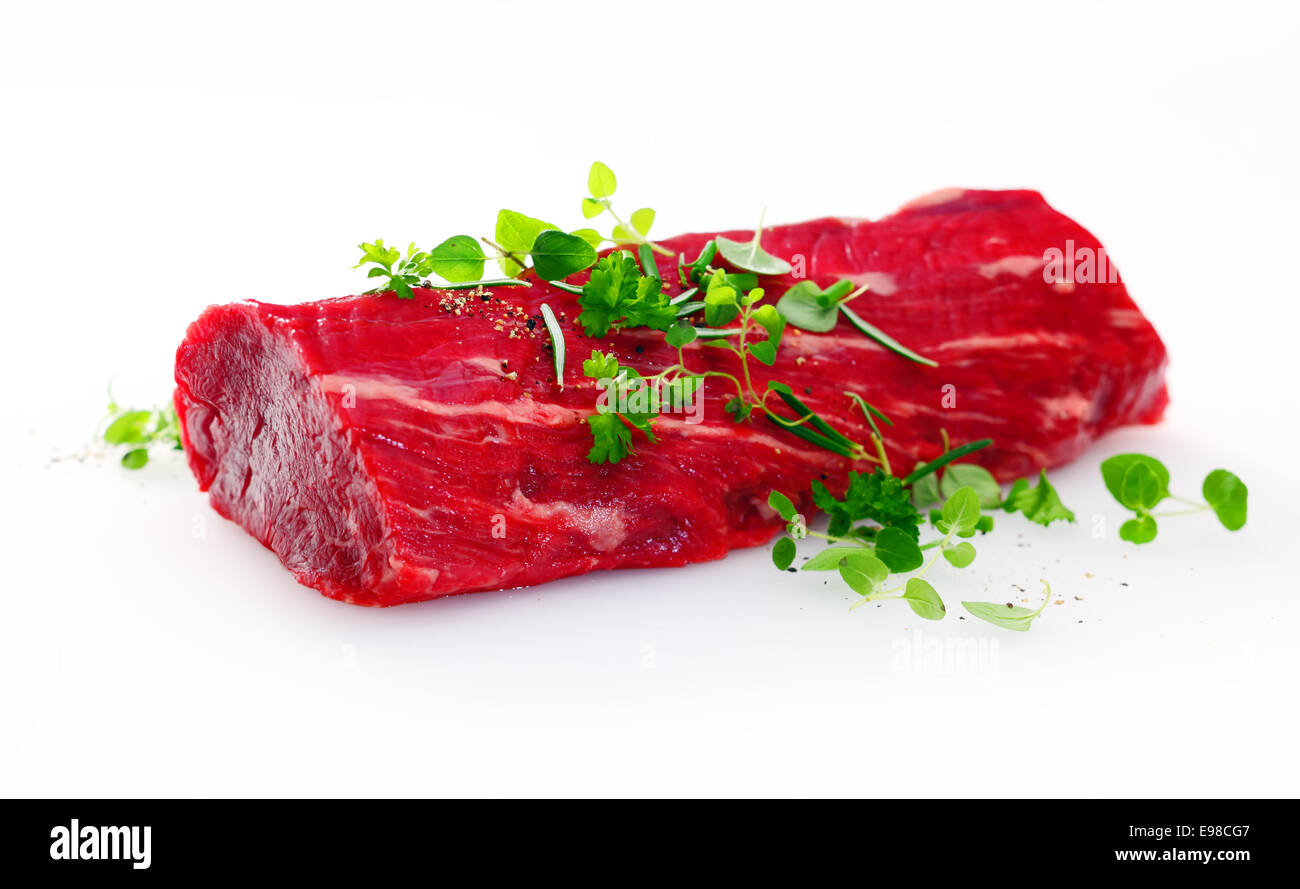 Healthy lean uncooked fillet steak garnished with fresh herbs in preparation for a gourmet meal on a white background Stock Photo