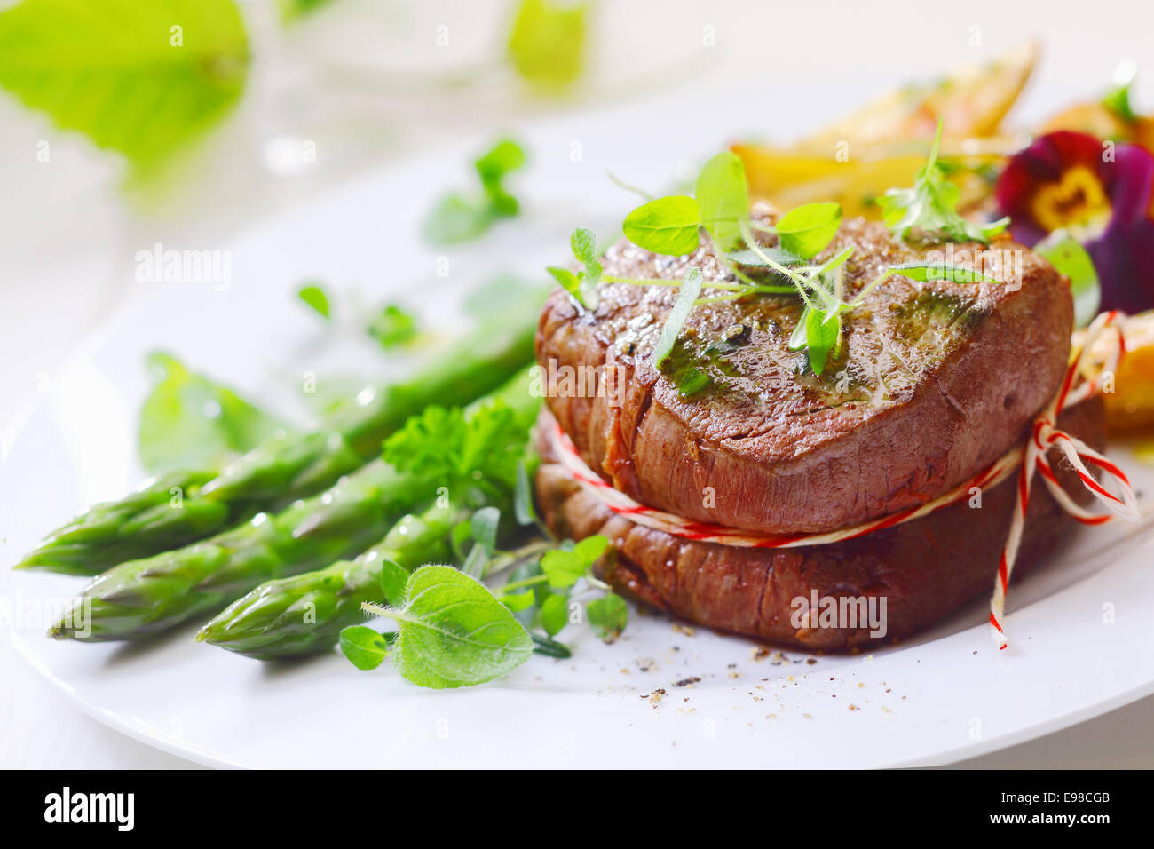 Medallion of roast fillet steak tied with string and served with fresh green asparagus tips and spears liberally garnished with Stock Photo