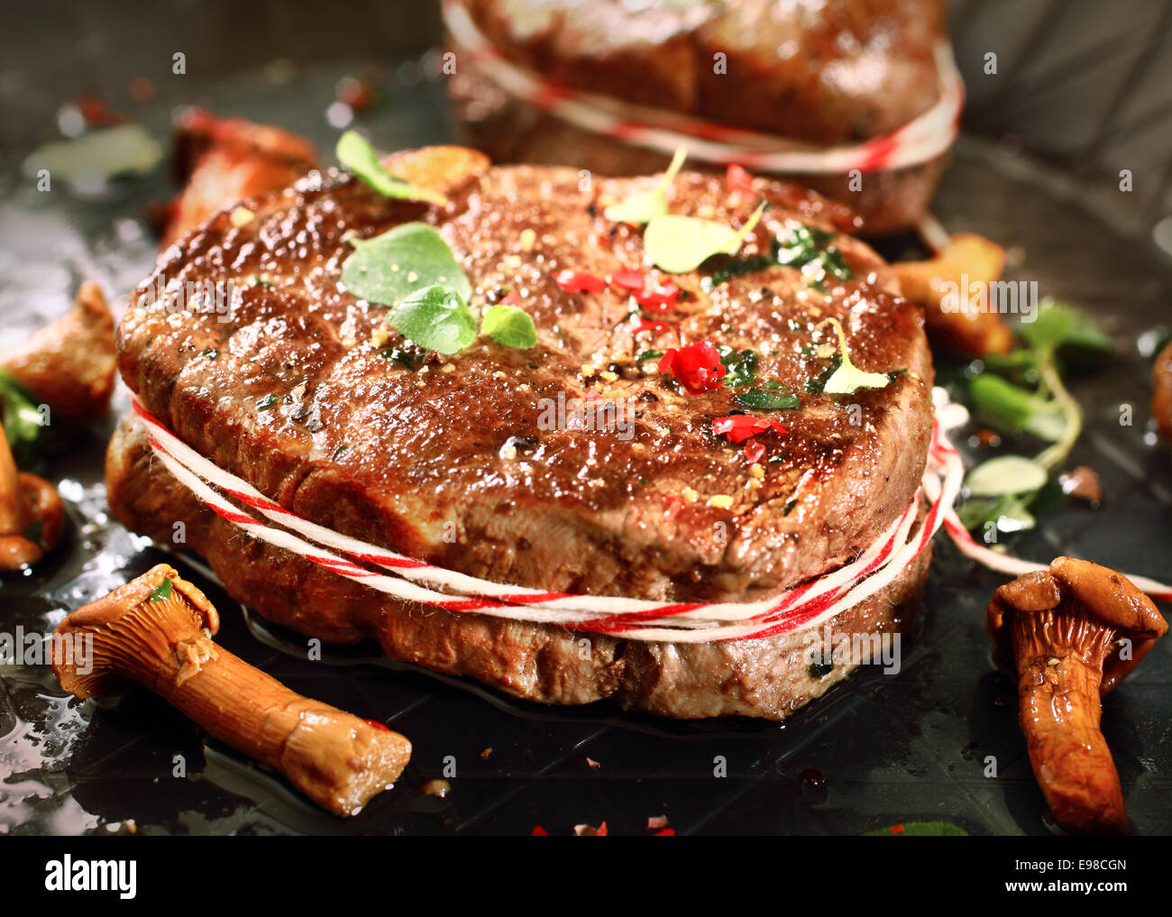 Closeup view of an appetizing grilled medallion of fillet and wild mushrooms seasoned with spice and fresh herbs Stock Photo