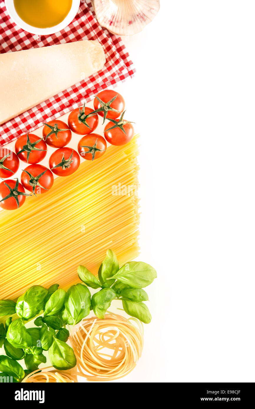 Fresh cooking ingredients for Italian pasta arranged on a white background with cheese, tomatoes, spaghetti, fresh basil leaves, fettucini and olive oil with a red and white checked napkin, copyspace Stock Photo