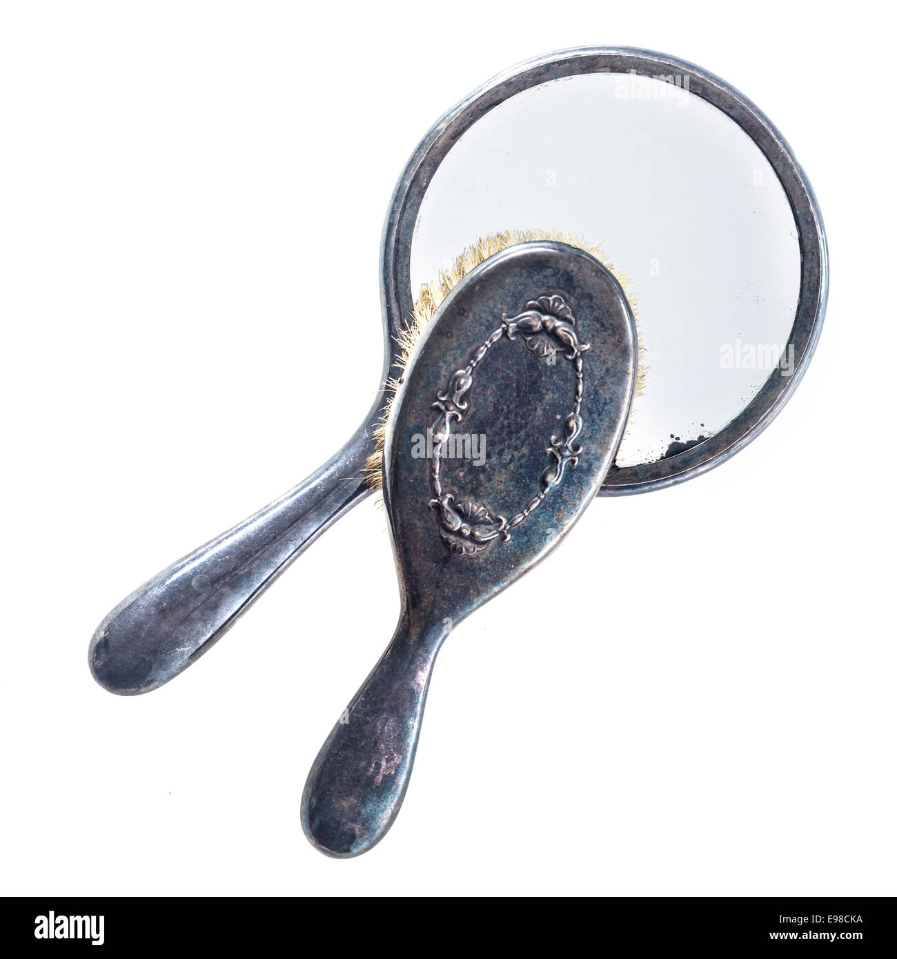 Close up view from above of a tarnished vintage grunge hairbrush and hand mirror, bygones from an old vanity set isolated on white Stock Photo