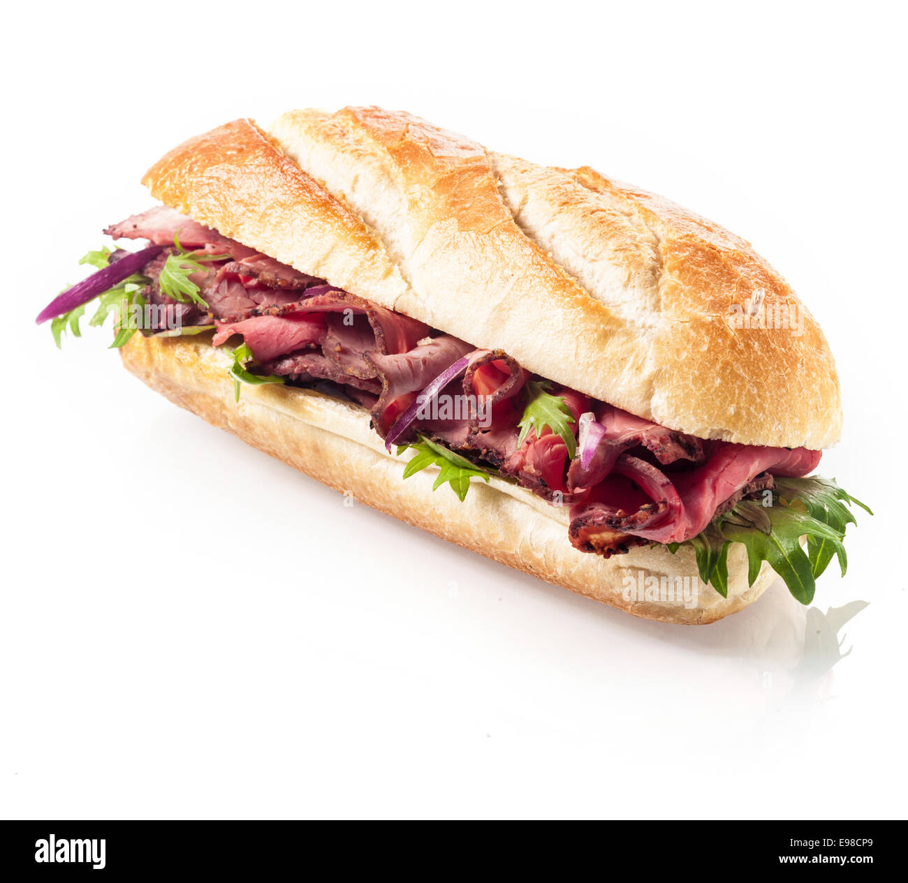 Healthy lean roast beef with leaves of fresh rocket on a freshly baked crusty roll or baguette viewed at an angle on a white background Stock Photo