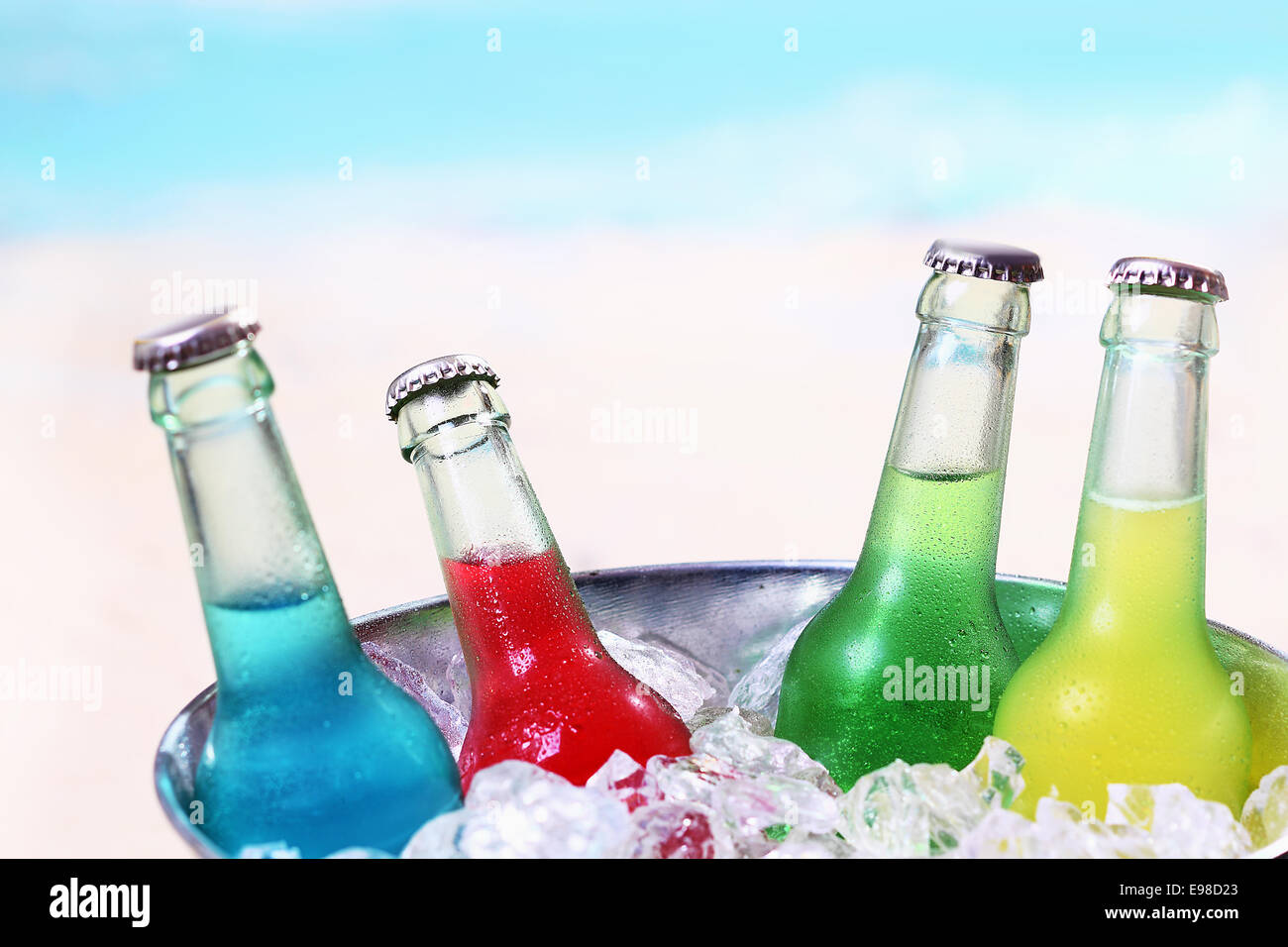 Colourful chilled soda drinks in unlabeled glass bottles standing in a metal container of crushed ice cubes for a summer party Stock Photo