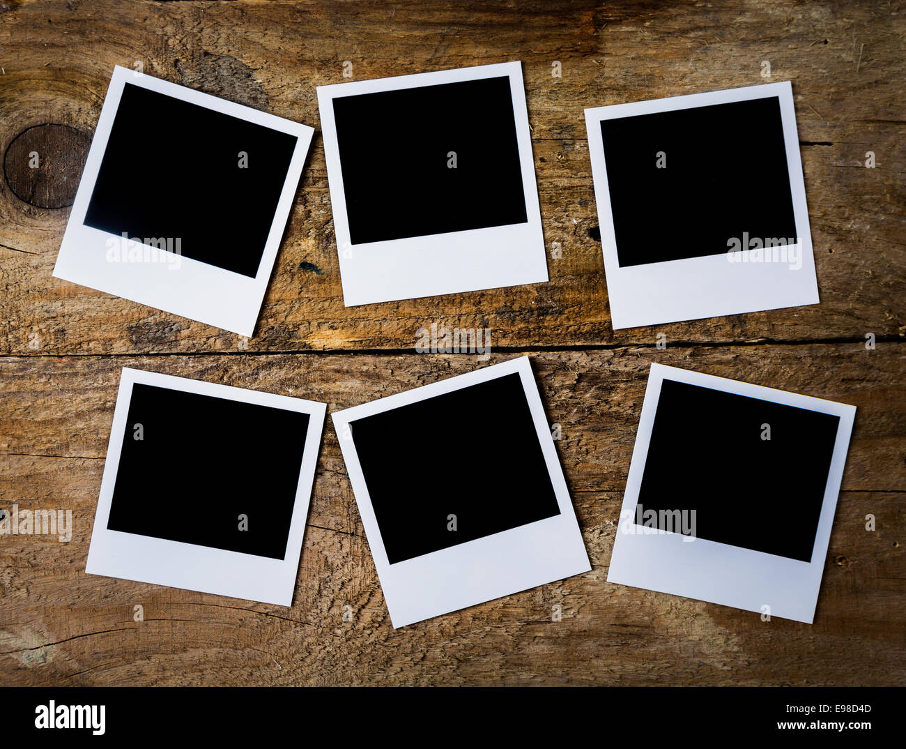 Overhead view of six retro blank instant photo frames with copyspace arranged on a rough textured wooden plank recalling memories of a bygone era or vacation Stock Photo
