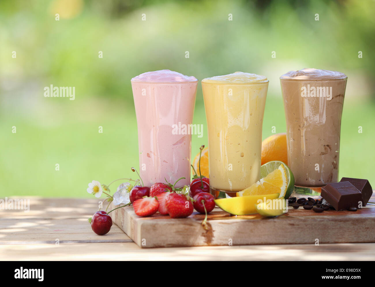 Three fruit or choclate smoothies or milkshakes with fresh organic ingredients including strawberries, cherries, citrus, coffee Stock Photo