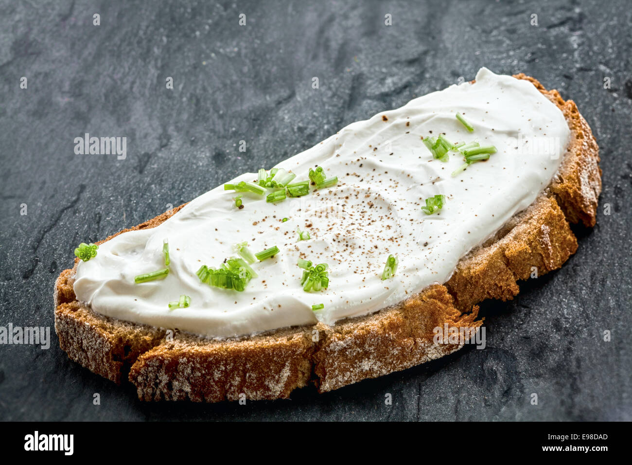Healthy low fat cream cheese and chopped chives on a slice of freshly baked rye bread, close up low angle view Stock Photo