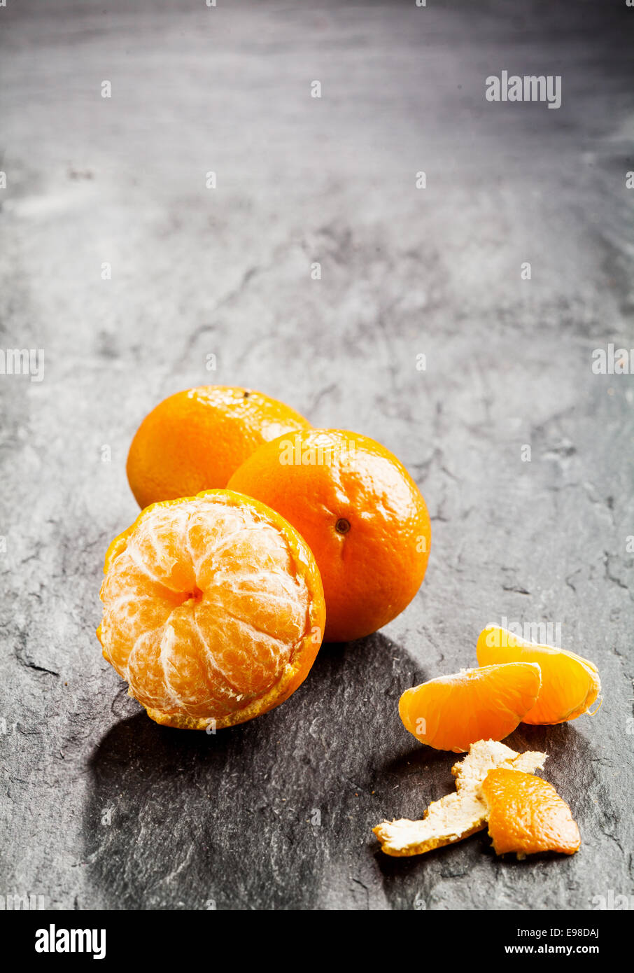 Peeled fresh sweet nectarine, tangerine or clementine with scattered loose  peel and segments on a dark background with copyspace Stock Photo - Alamy