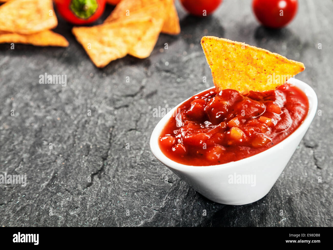 Serving of hot spicy salsa sauce made with tomato and chili peppers in a bowl with corn tortillas or nachos to dip for a savory Stock Photo