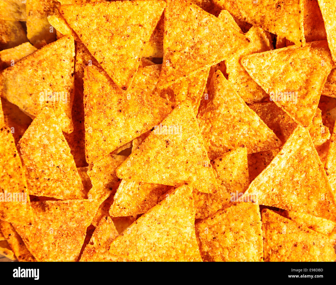 Background of crisp crunchy spicy corn tortillas or nachos with their ditsinctive triangular shape for a tasty snack Stock Photo