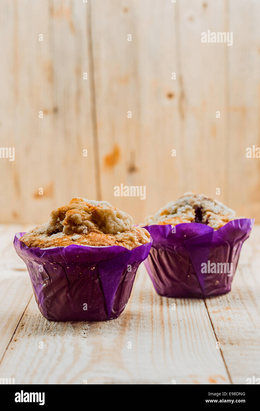 Two freshly baked healthy muffins with muesli and nuts in colourful purple paper cups for a healthy breakfast or teatime snack Stock Photo