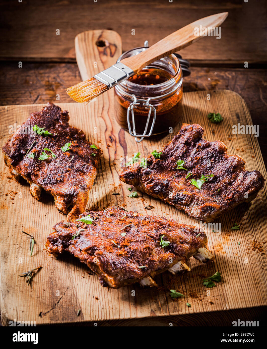 Three portions of spicy grilled ribs basted with a savory aromatic sauce and garnished with herbs for a delicious meal Stock Photo
