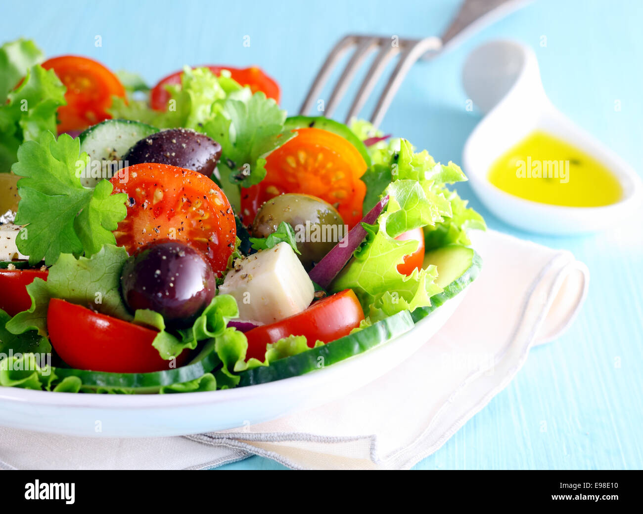 Healthy fresh Greek salad with olives and feta cheese nestling on a bed of crisp lettuce with tomato, closeup partial view of the dish Stock Photo