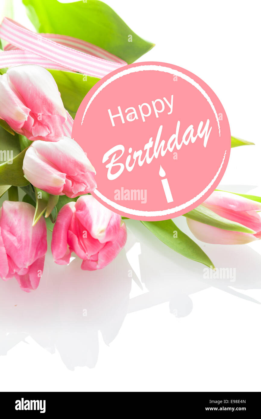 Pretty feminine Happy Birthday greeting with a festive pink rosette and a bouquet of beautiful fresh pink tulips on a white background, closeup perspective Stock Photo