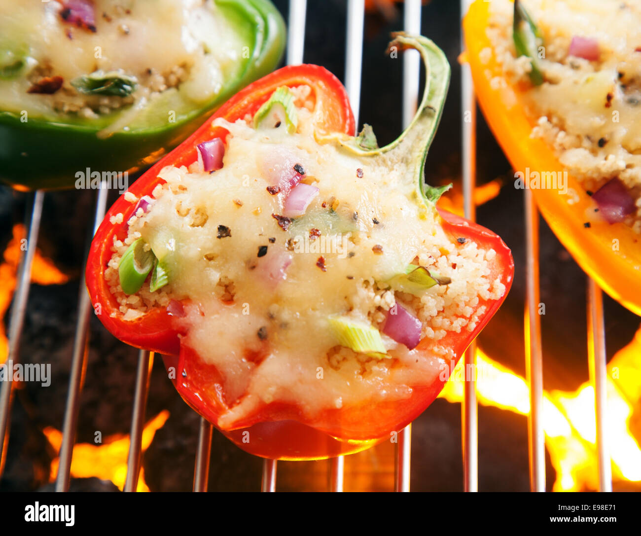 Savory stuffed sweet bell pepper with melted cheese grilling over the hot glowing coals on an outdoor barbecue, close up overhead view Stock Photo