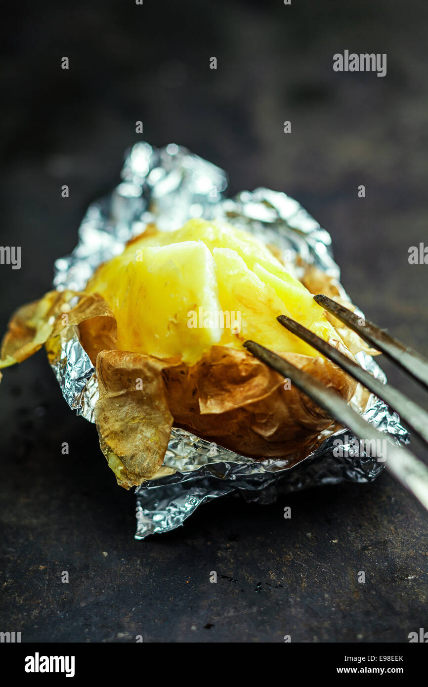 Half eaten delicious baked jacket potato in aluminium foil for a