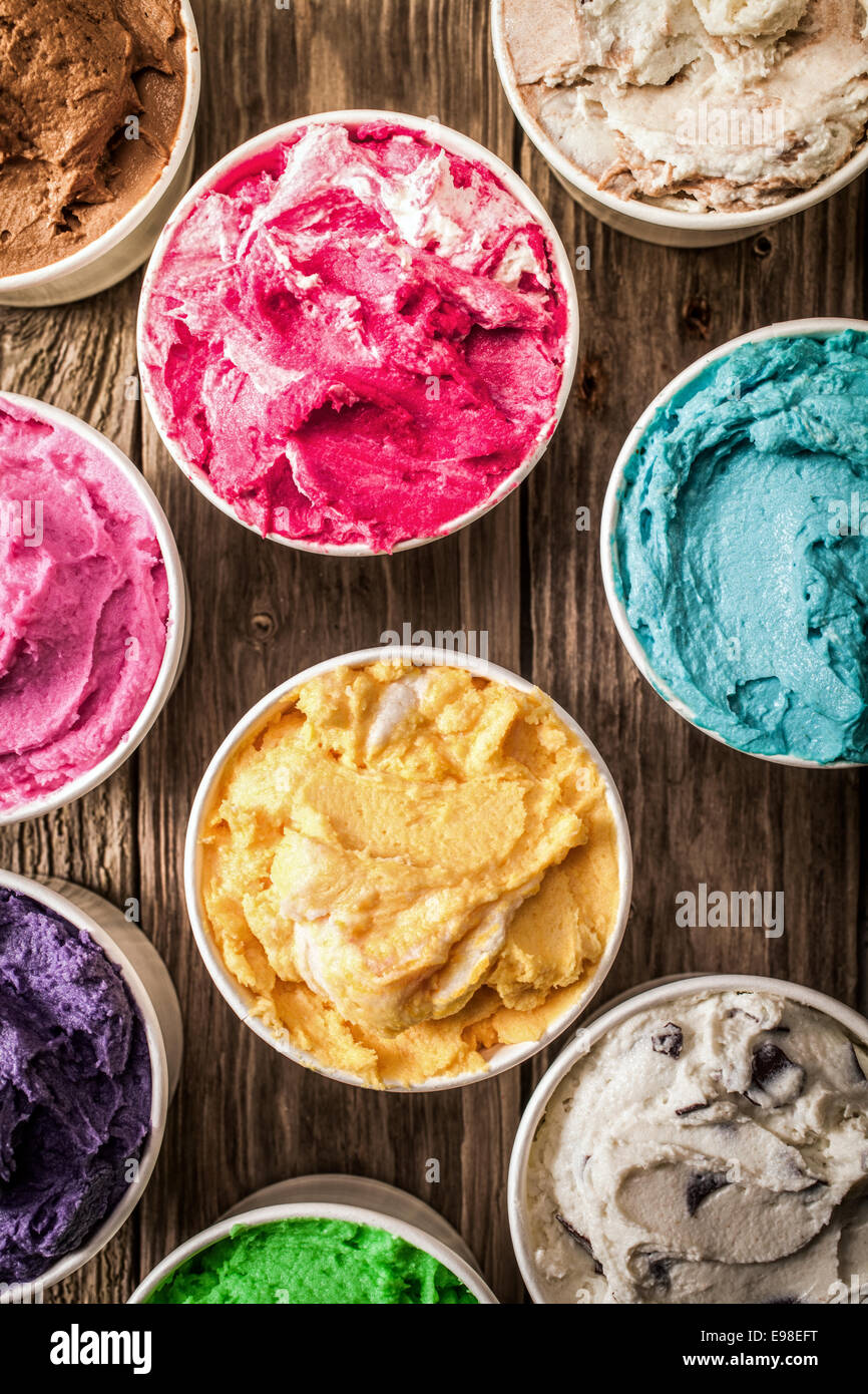 Overhead view of a selection of colorful tubs of Italian ice cream in a variety of flavors on a rustic wooden surface for a delicious summer dessert Stock Photo