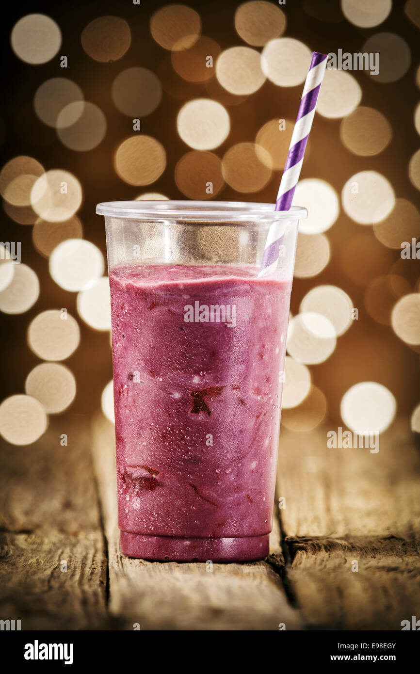Festive blueberry smoothie blended with yogurt and ice cream for a refreshing summer drink against a bokeh of sparkling lights Stock Photo