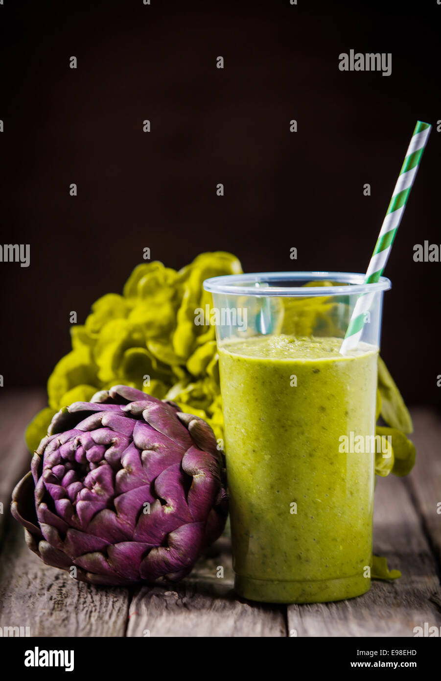 Healthy green artichoke smoothie blended with lettuce and yogurt and served with fresh ingredients on a wooden table over a dark background with copyspace Stock Photo