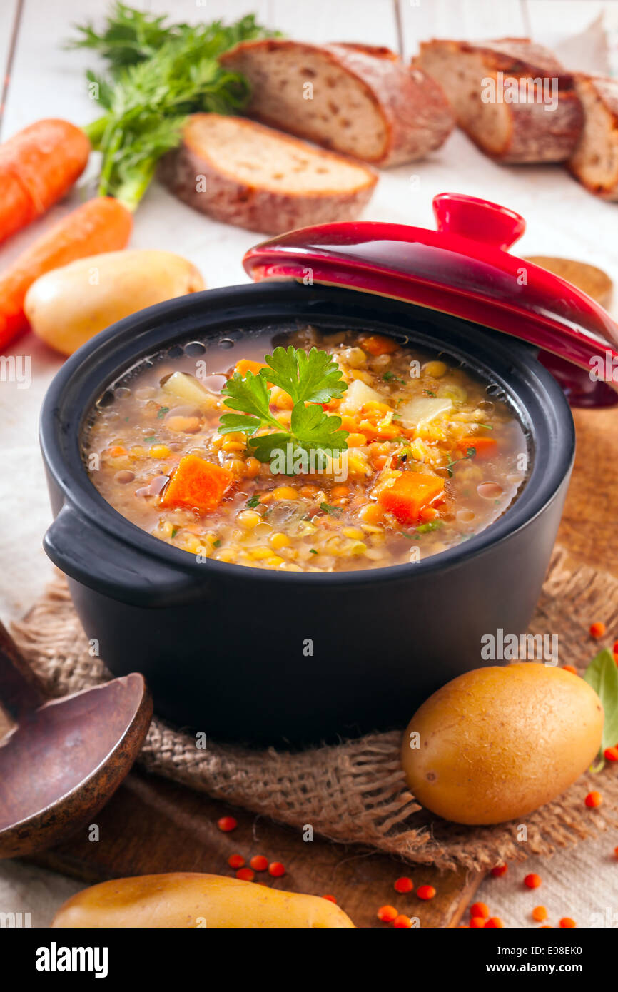Overhead view of a thick wholesome vegetarian vegetable and lentil stew served with sliced bread on bricks Stock Photo
