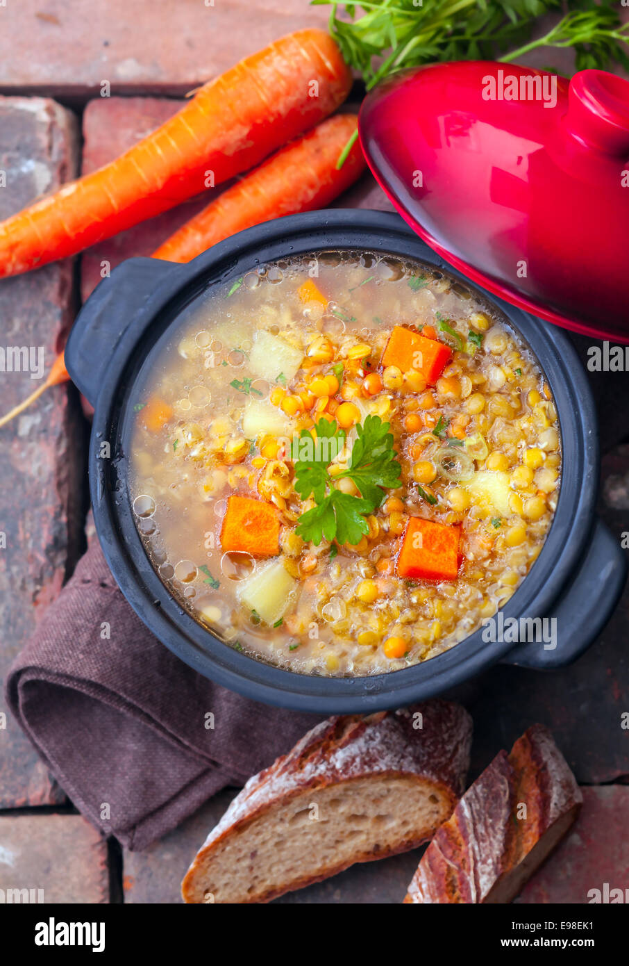 Overhead view of a thick wholesome vegetarian vegetable and lentil stew served with sliced bread on bricks Stock Photo
