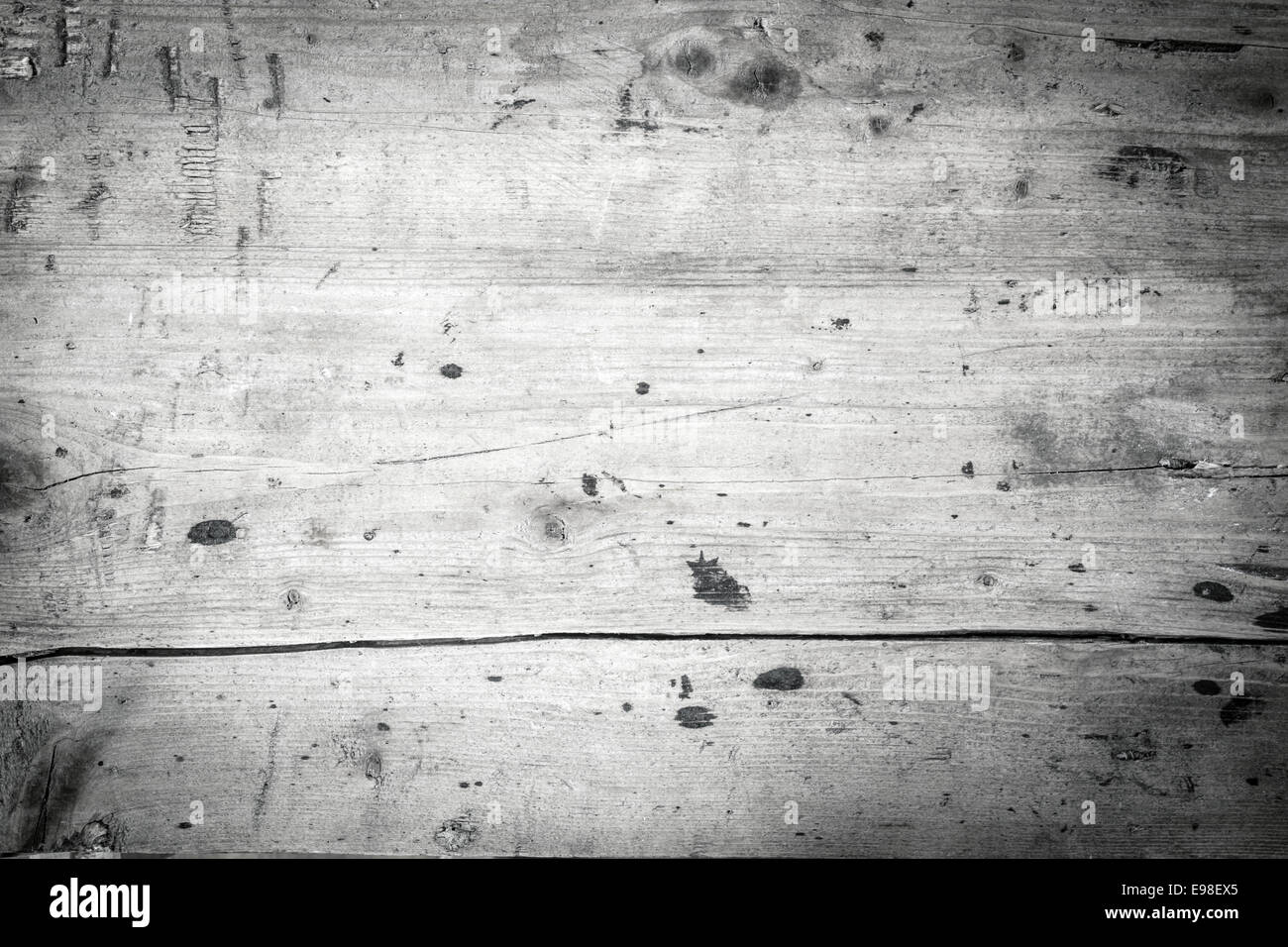 Monochrome greyscale background of old wooden boards with a smooth texture, stain spots, a large crack and corner vignette Stock Photo
