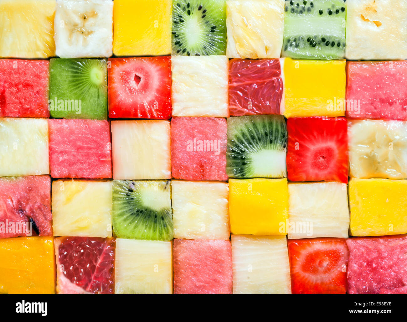 Seamless background pattern and texture of colourful fresh diced tropical fruit cubes arranged in a geometric pattern with melon, watermelon, banana, pineapple, strawberry, kiwifruit and grapefruit Stock Photo