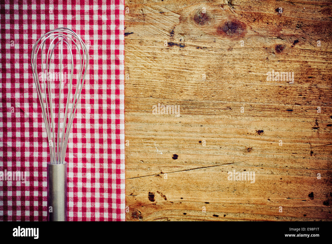 Metal cooking whisk, or balloon whisk, lying on a fresh red and white checkered napkin on a