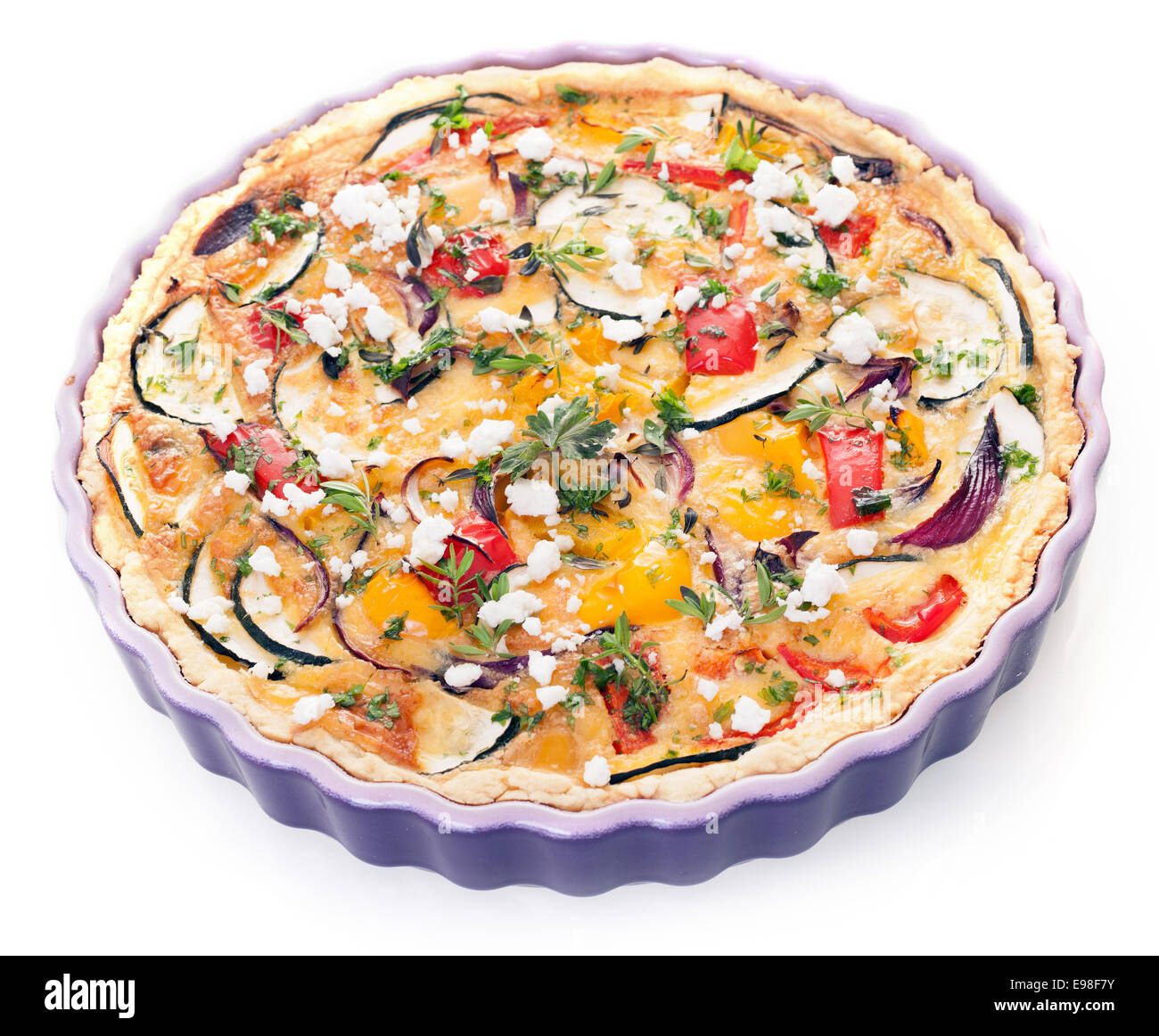 Vegetarian eggplant quiche in a decorative fluted oven dish with egg, cheese, peppers, tomato and herbs for a healthy meal, high angle isolated on white Stock Photo