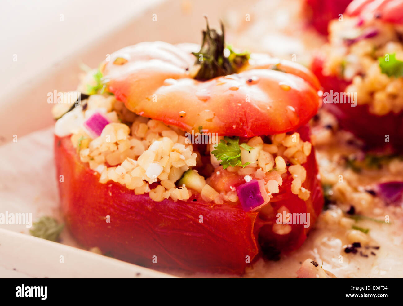 Delicious oven baked stuffed tomatoes filled with a couscous grain, onion, and herbs for a healthy appetizer or vegetarian meal Stock Photo
