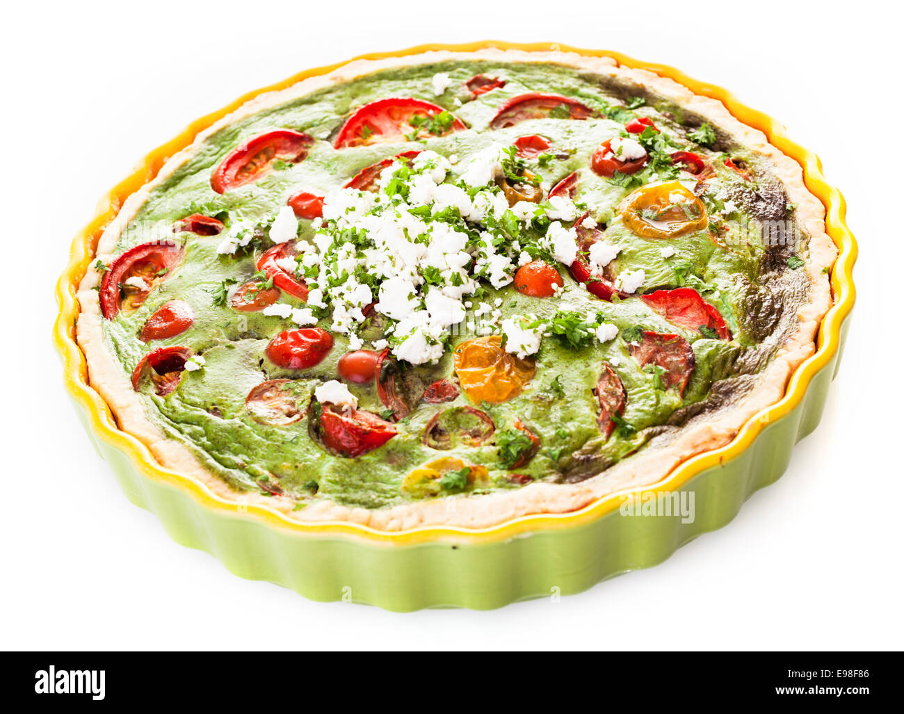 Savory egg, herb, tomato and cheese vegetarian quiche in a pastry crust served in a fluted pie dish on a white background Stock Photo