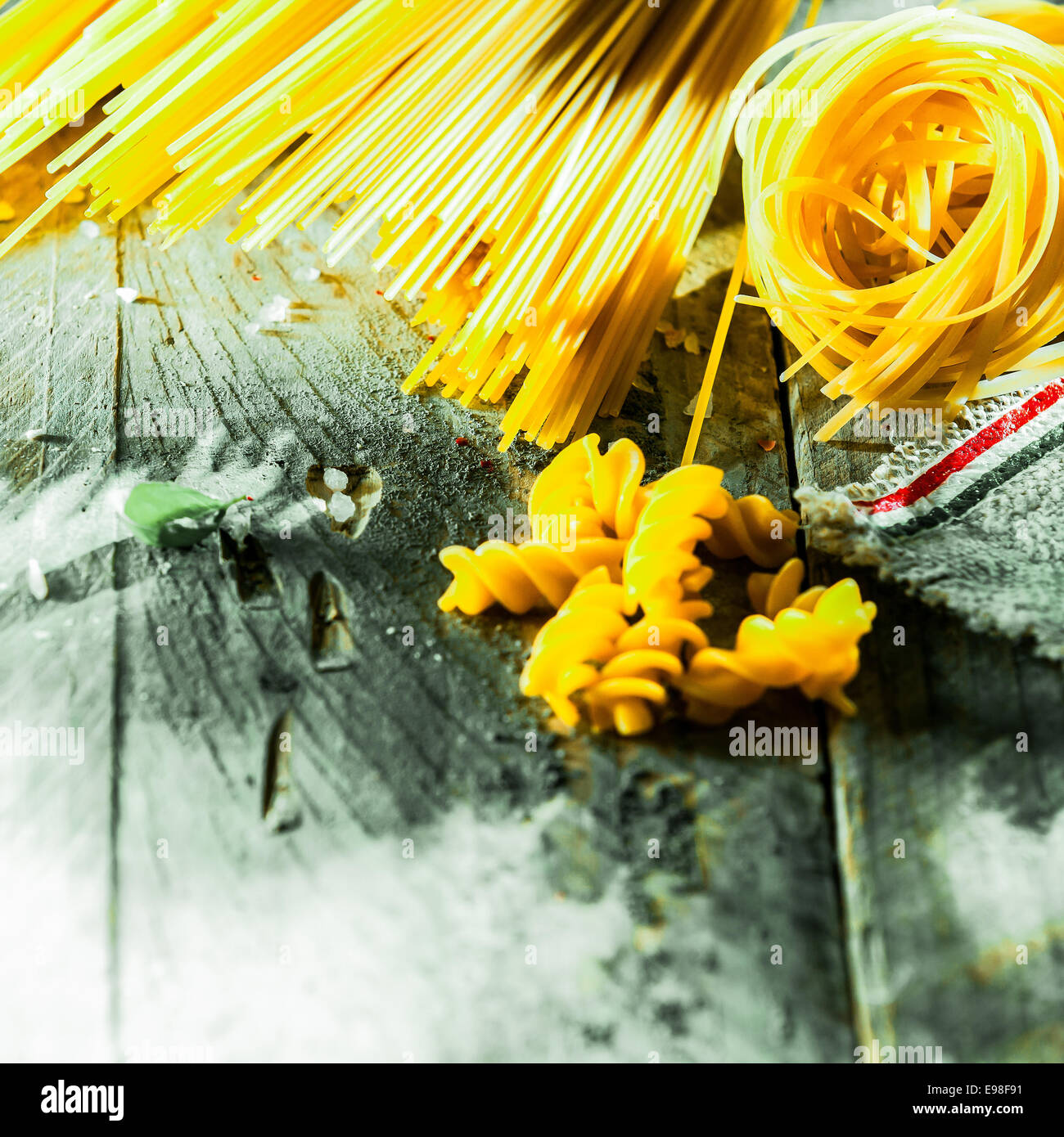 Assorted dried Italian pasta lying on old weathered wooden boards with spaghetti, fusilli, and linguini Stock Photo