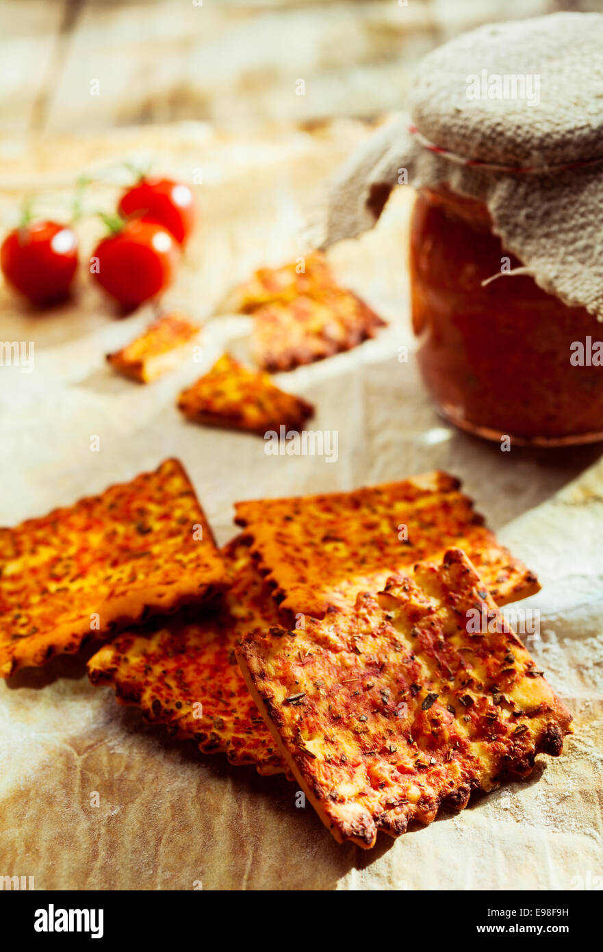 Crisp spicy Italian crackers flavored with cheese on an old wooden table with a jar of preserve Stock Photo