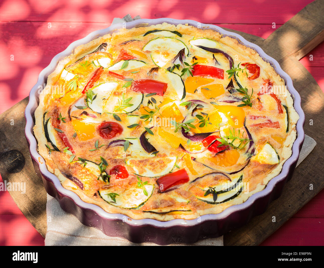 Delicious healthy vegetarian cuisine with a savory quiche with eggplant, peppers, egg custard, herbs and cheese in a decorative Stock Photo