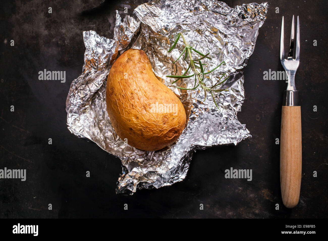 Delicious whole jacket baked potato lying on its crumpled silver