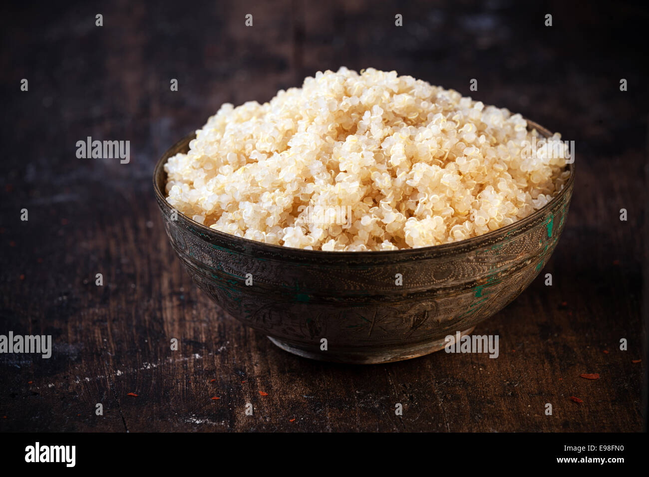 Side angle view of a heaped rustic bowl of healthy cooked quinoa, a pseudo-cereal whose seeds are rich in protein and nutrients Stock Photo