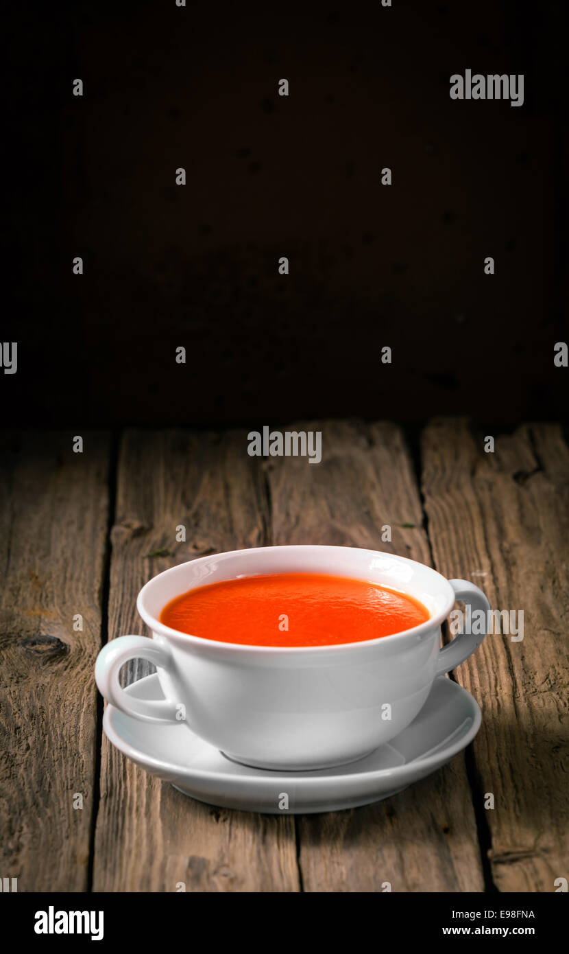 Plain white ceramic bowl of delicious hot tomato soup for a cold winter night served on rustic wooden boards with copyspace above Stock Photo