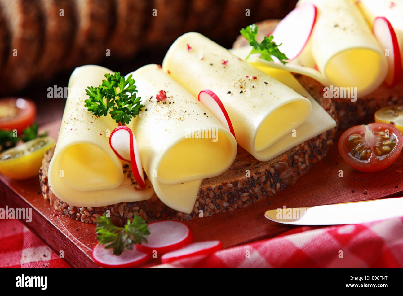 Tasty gouda cheese sandwich on wholegrain bread topped with slice radish and parsely for a healthy country lunch, close up view Stock Photo