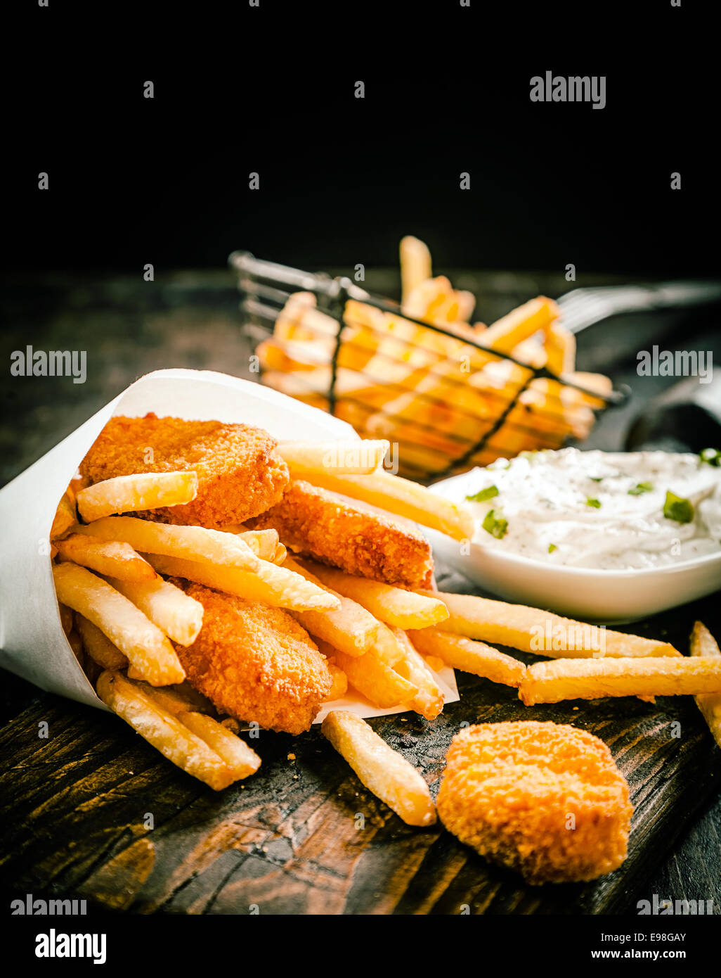 Deep fried takeaway crumbed fish portions and golden potato chips served in a disposable paper
