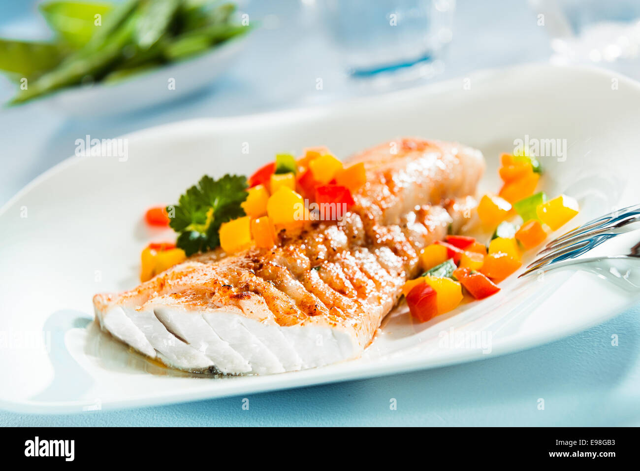 Delicious healthy grilled fish fillet served on a platter with a colorful fresh salad for a tasty seafood dinner Stock Photo