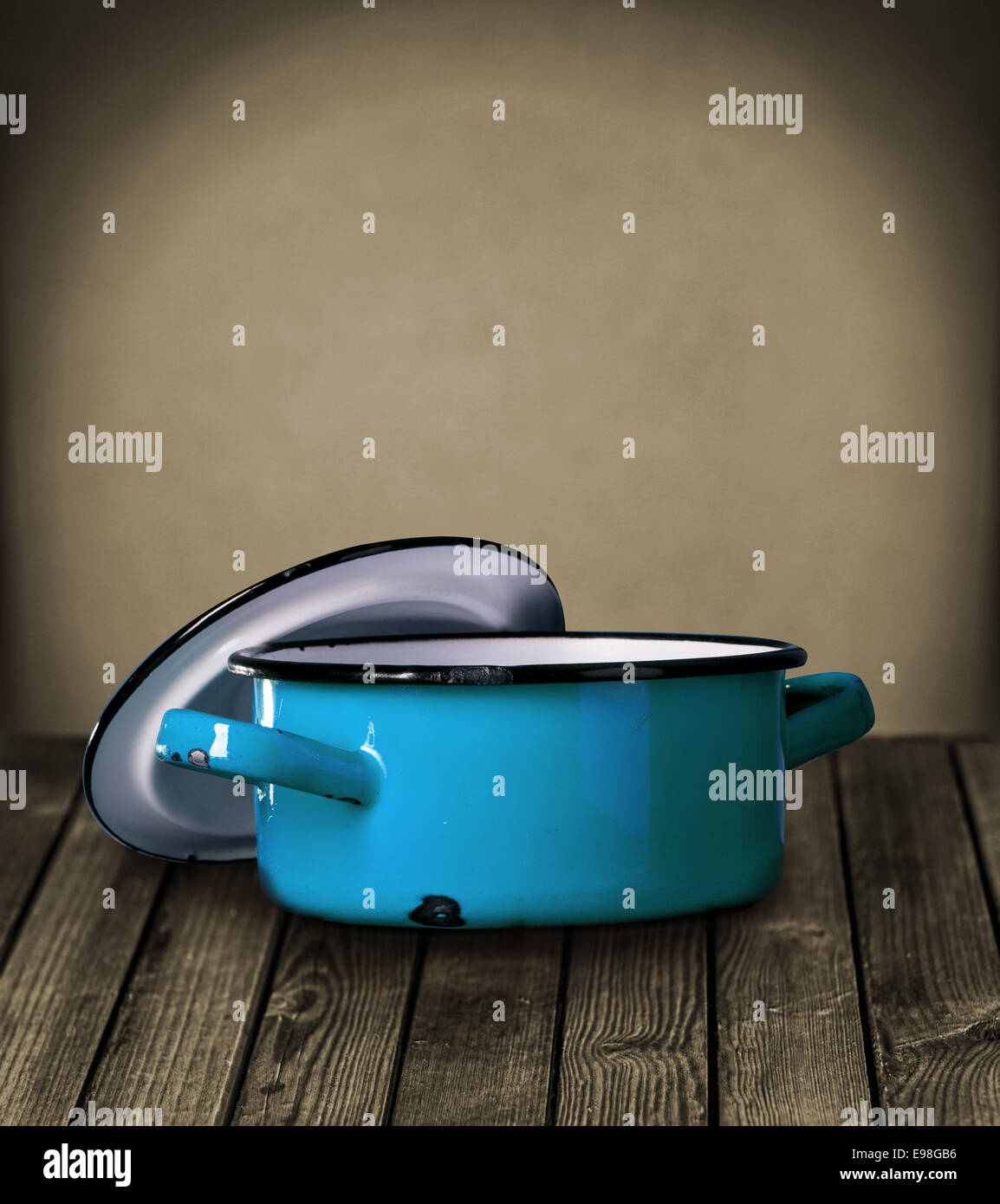 https://c8.alamy.com/comp/E98GB6/old-blue-enameled-pot-and-lid-standing-on-a-rustic-wooden-table-against-E98GB6.jpg