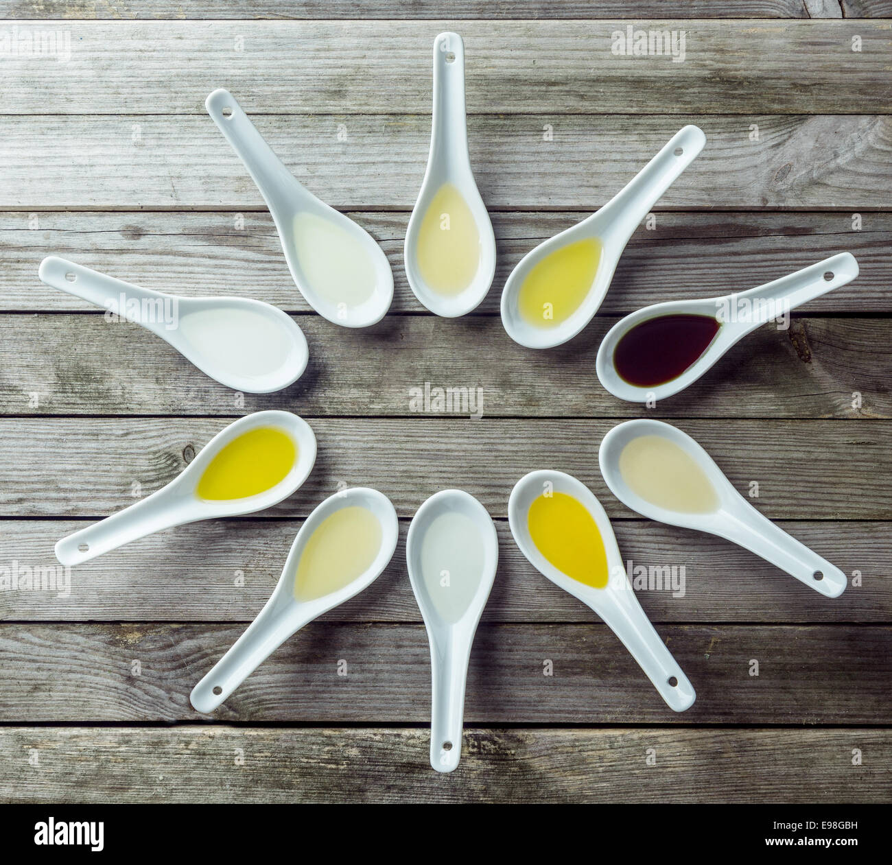 Several Chinese soup spoon filled with different colored liquid on wooden surface Stock Photo