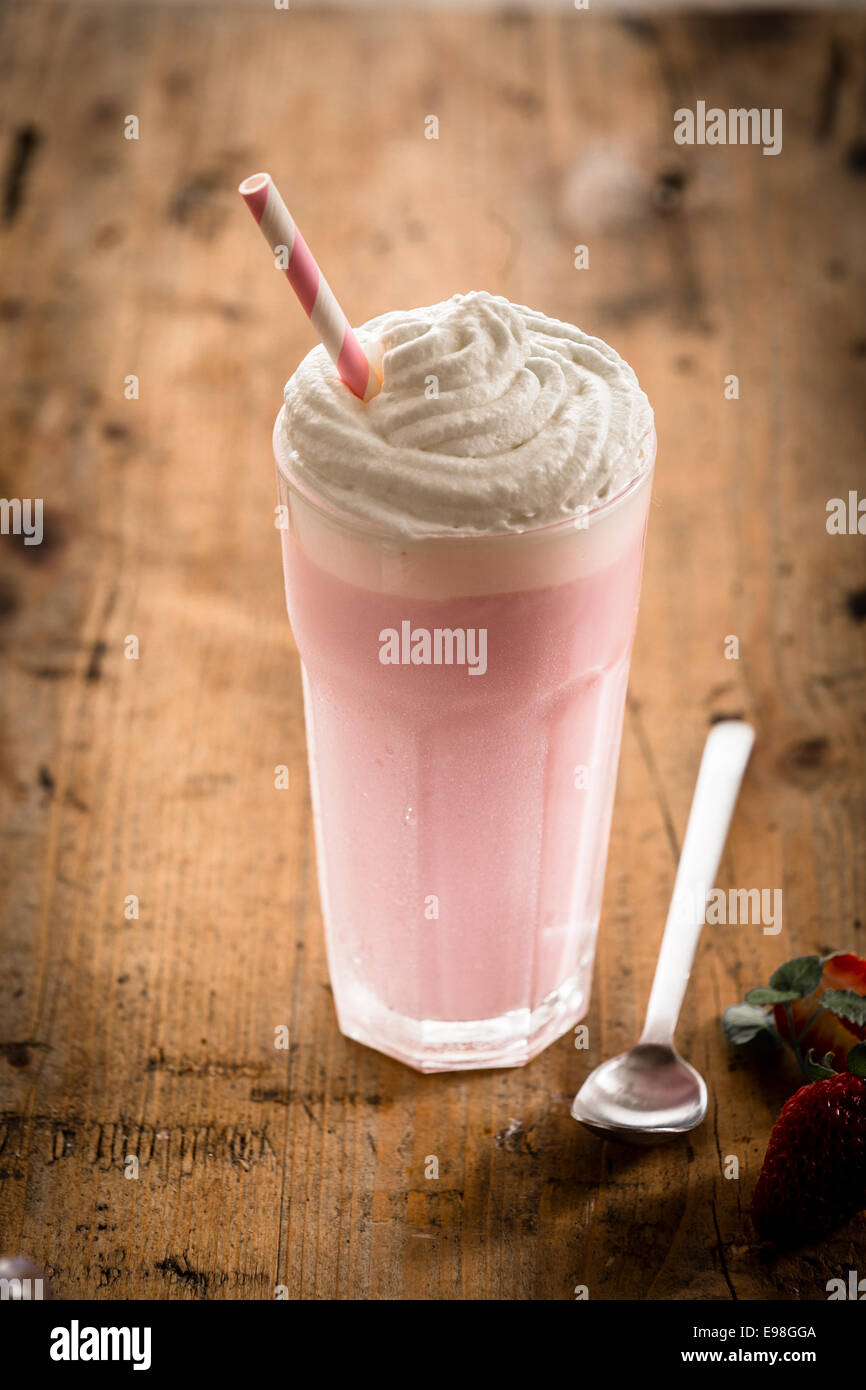 Delicious berry smoothie or milkshake served in a tall glass topped with a twirl of whipped cream or frozen yoghurt, high angle Stock Photo