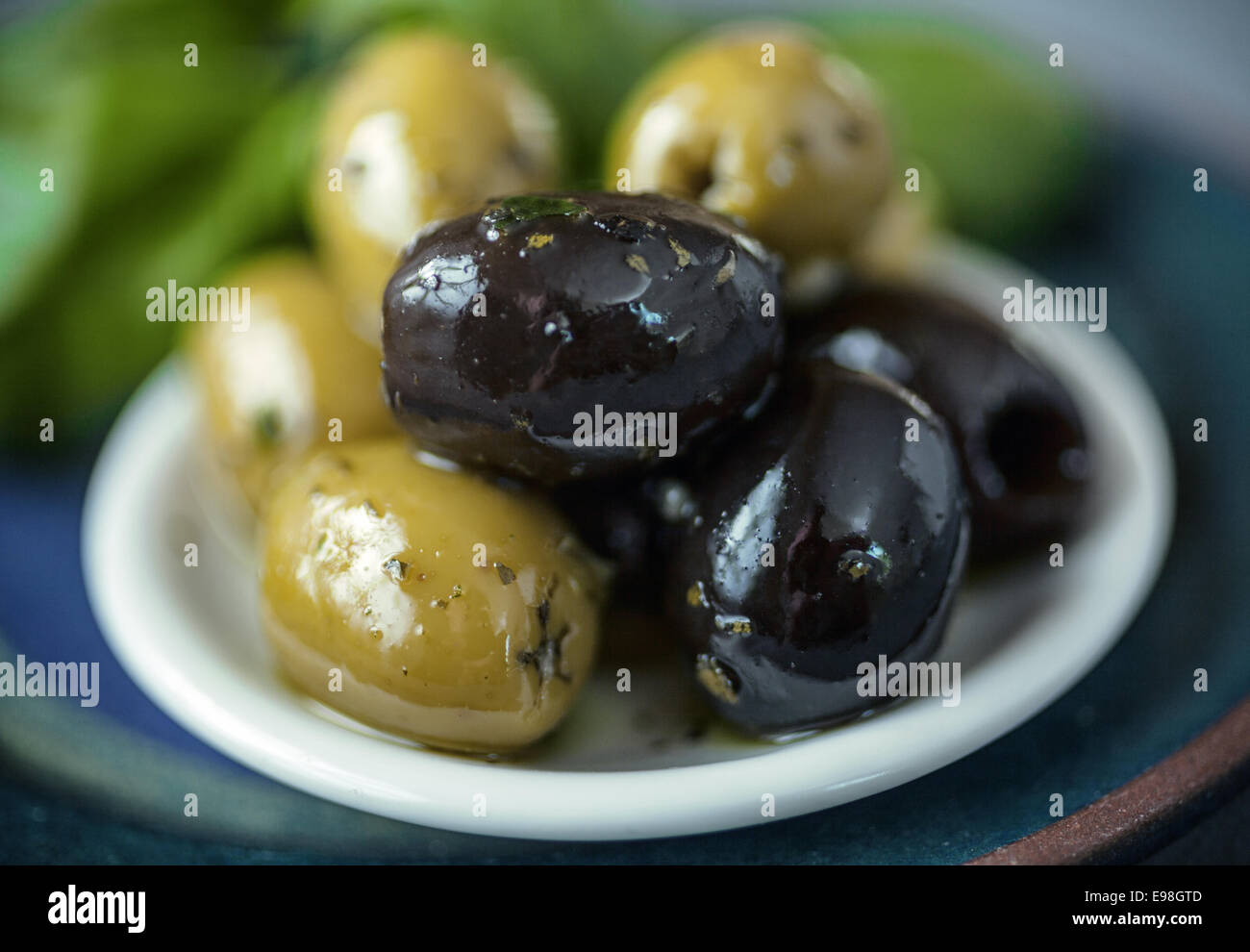 Small bowl of cured fresh black and green olives served as snacks and appetizers with shallow dof Stock Photo