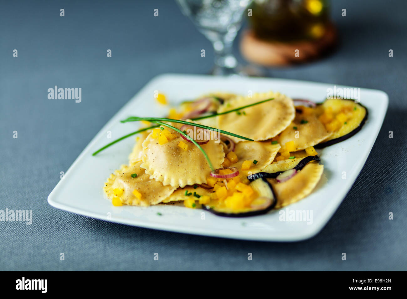 Vegetarian Italian ravioli pasta with grilled or roasted slices of eggplant or aubergine served on a modern square plate topped Stock Photo
