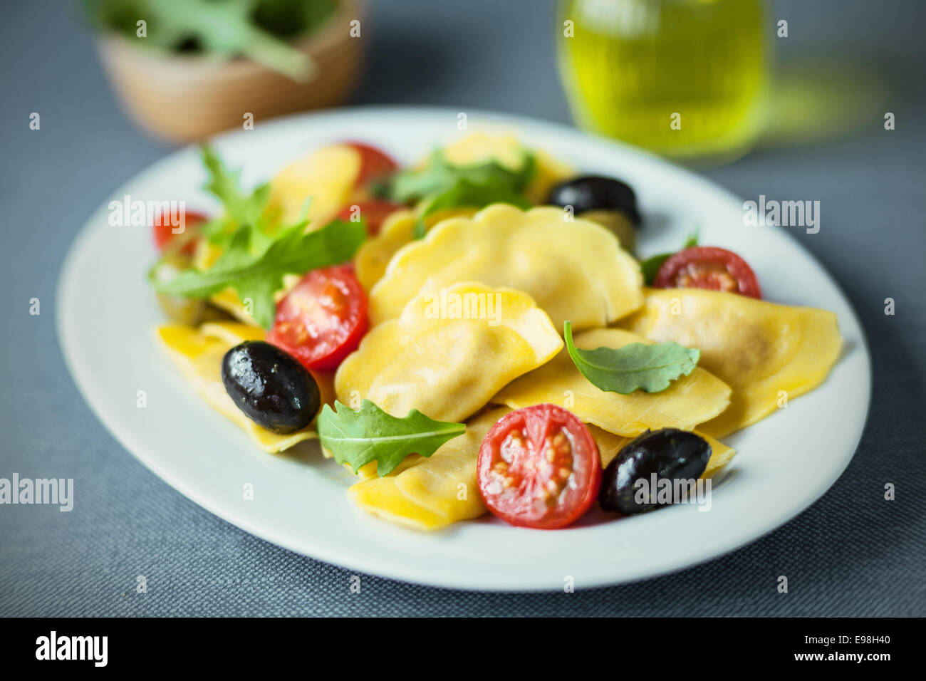 Italian ravioli salad with rocket , cured black olives and fresh cherry tomato on an oval plate, closeup with shallow dof Stock Photo