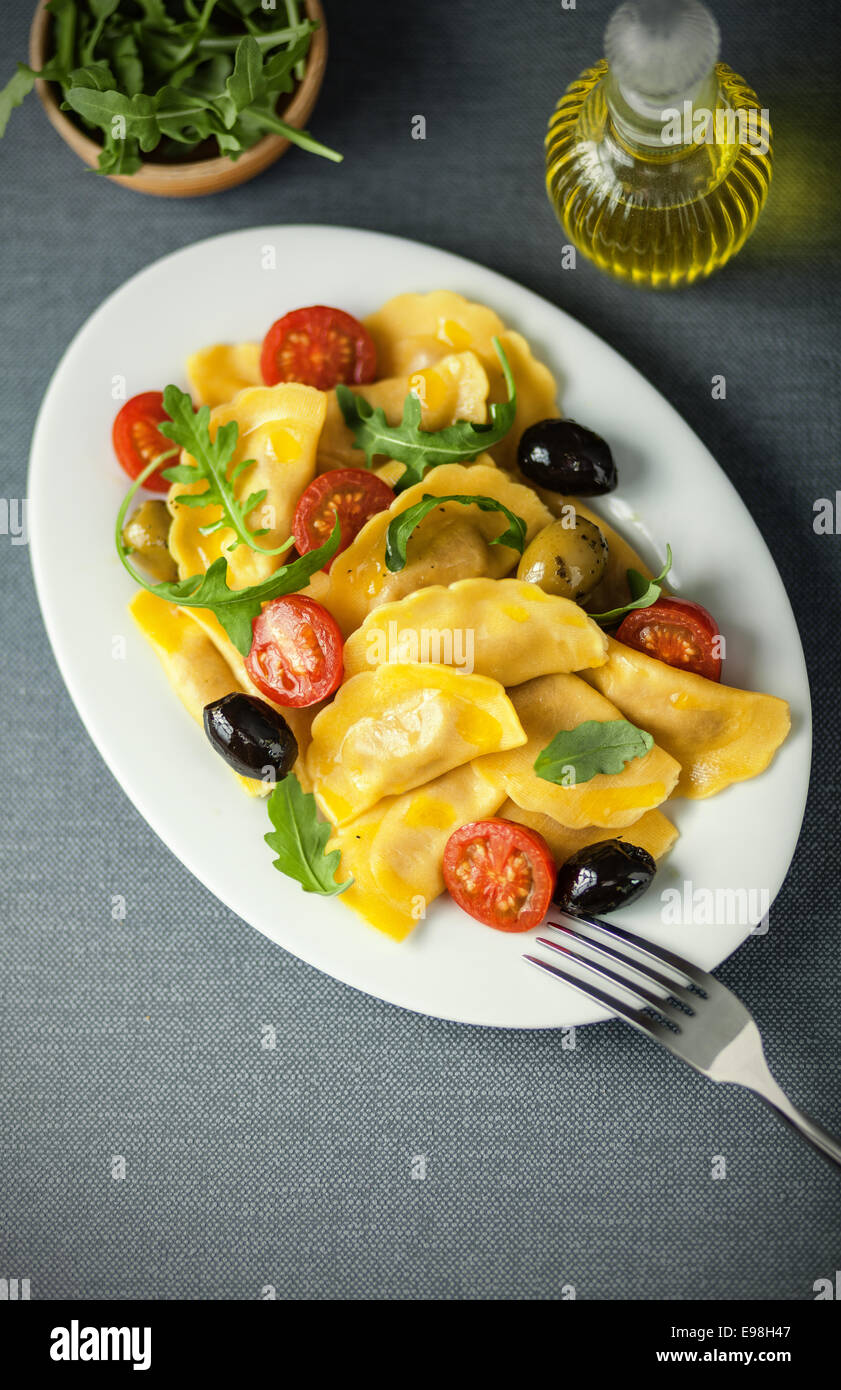 Italian ravioli pasta with olives, tomato and fresh rocket leaves