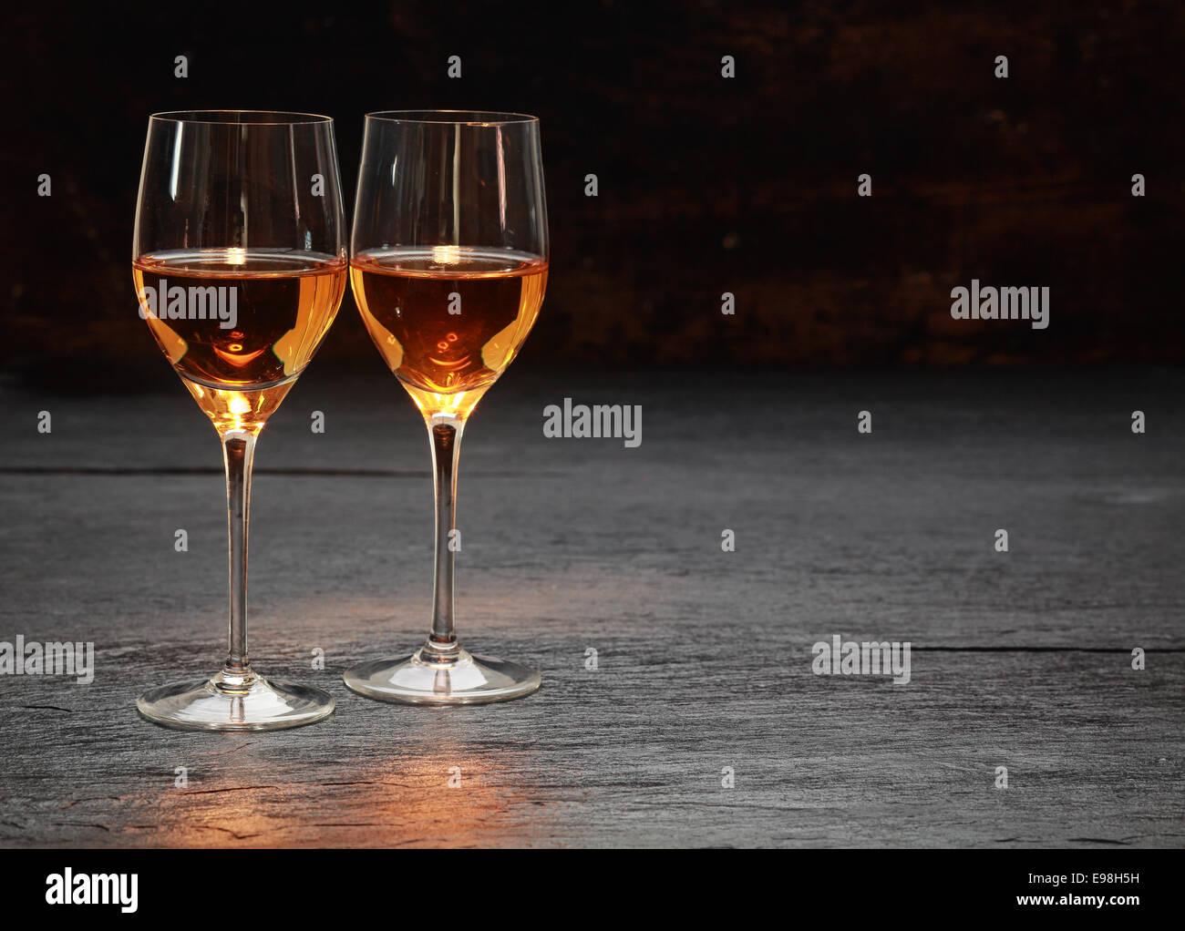 Pair of half-full half-empty wine glasses on stone surface Stock Photo