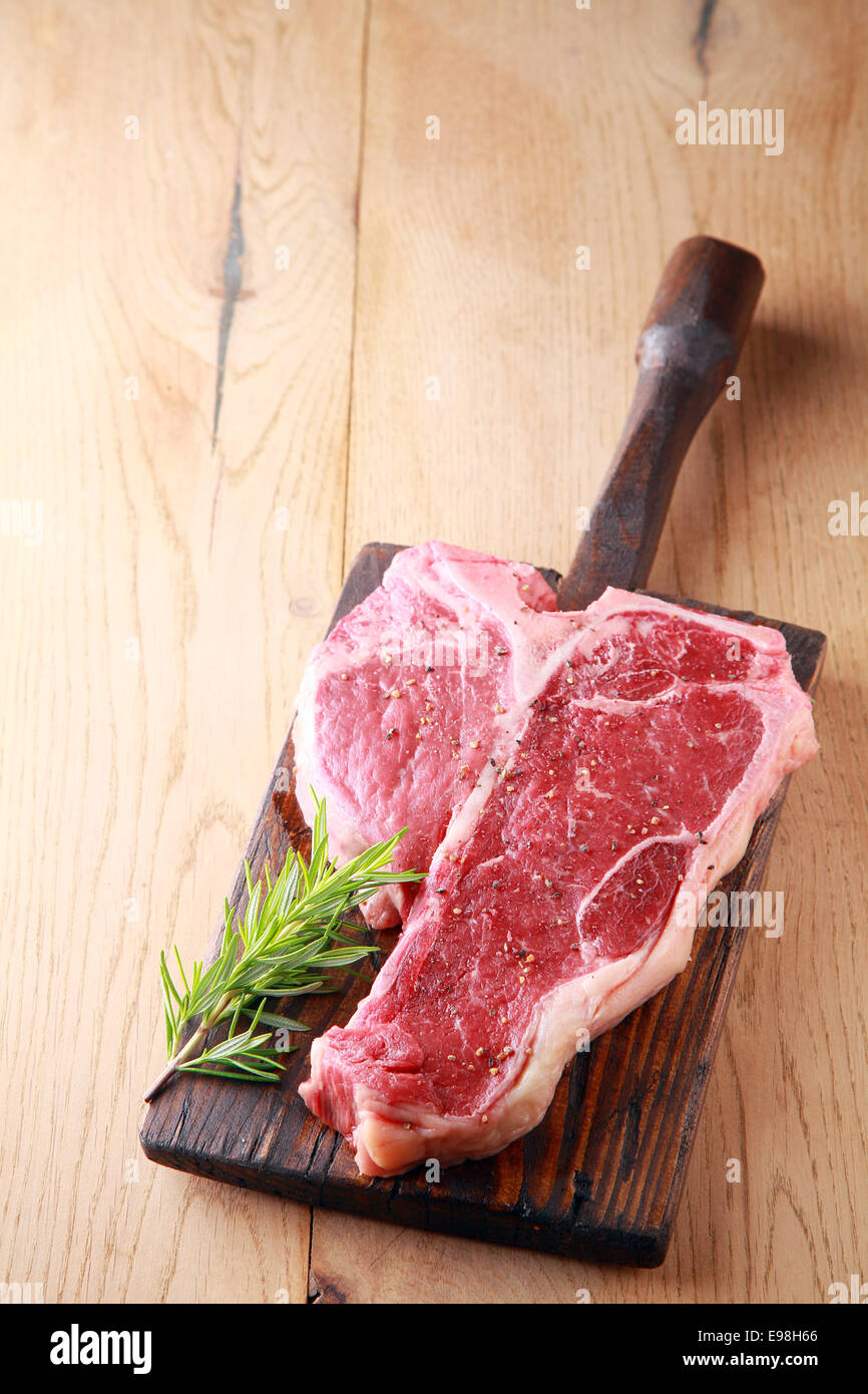 An uncooked tender lean porterhouse steak with a sprig of fresh